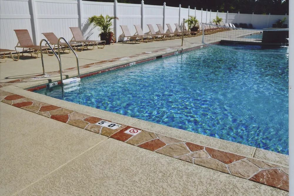 Commercial swimming pool with volleyball net and lounge chairs