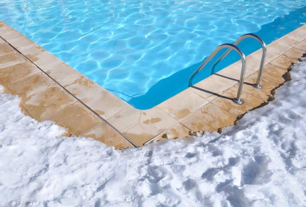 Outdoor inground pool with white snow beside it