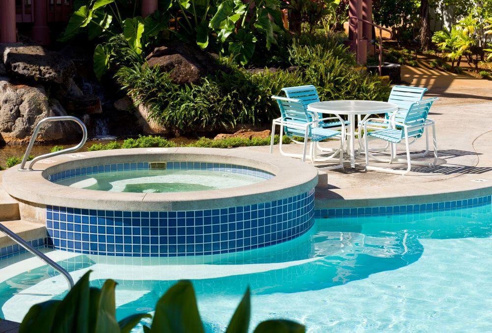 Pool and hot tub with table and chairs in the pool deck