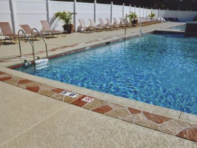 Commercial swimming pool with volleyball net and lounge chairs