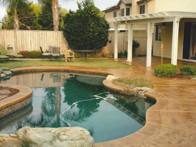 Residential backyard pool deck with stained concrete surface