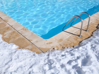 Outdoor inground pool with white snow beside it Outdoor inground pool with white snow beside it