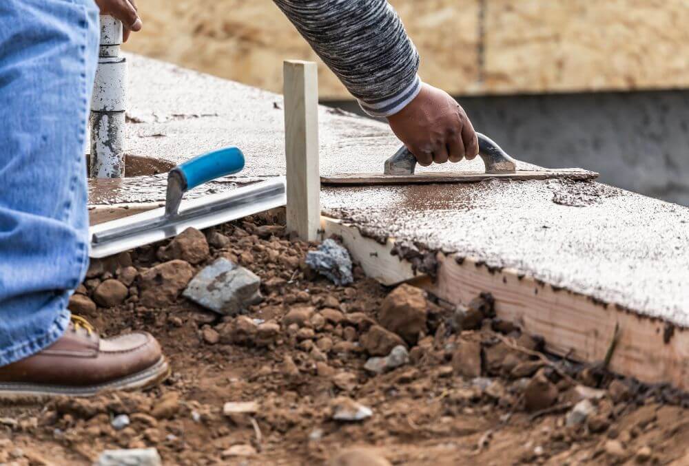 Contractor flattening concrete in a pool coping