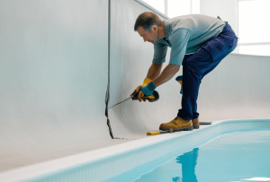 contractor fixing cracks on the concrete swimming pools using tools